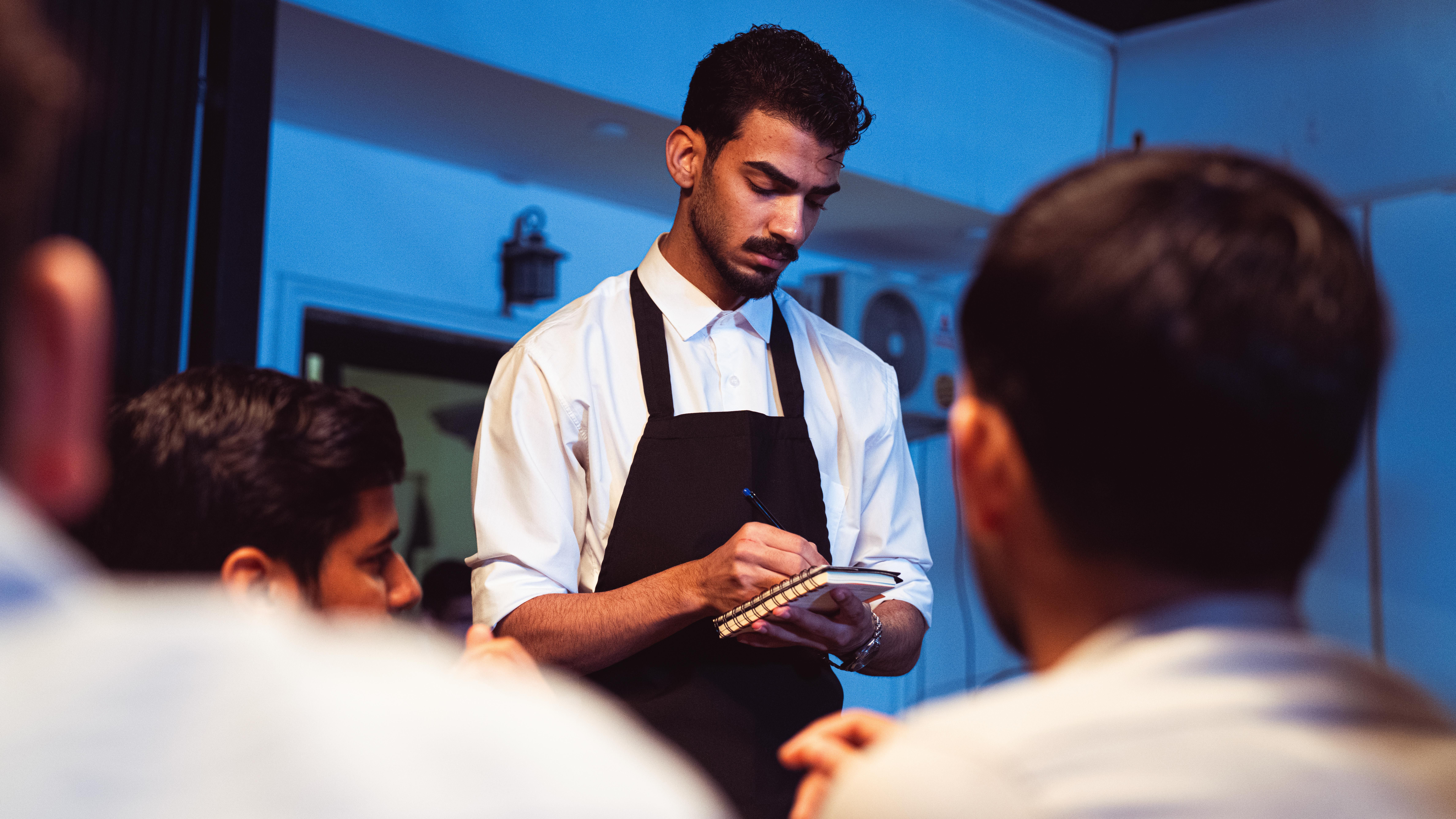 Attentive waiter writing down a customer's order in a cozy indoor restaurant